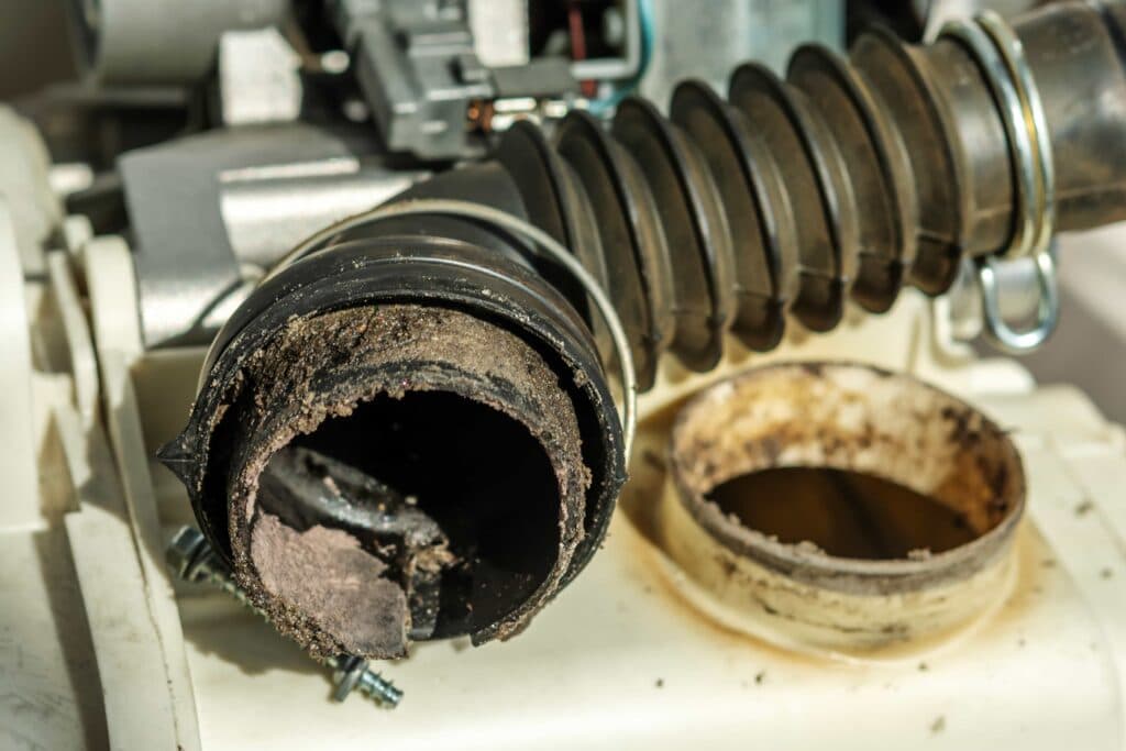 Hire a Pro Dryer Vent Tech: Avoid Fires & Boost Airflow 2 A clogged washing machine pipe filled with debris requiring professional appliance repair service in Ocala, FL.